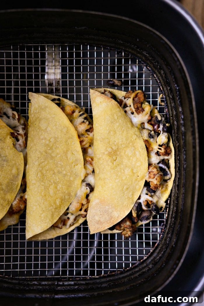 Freshly air fried crispy chipotle chicken black bean tacos removed from the air fryer, ready to be served.