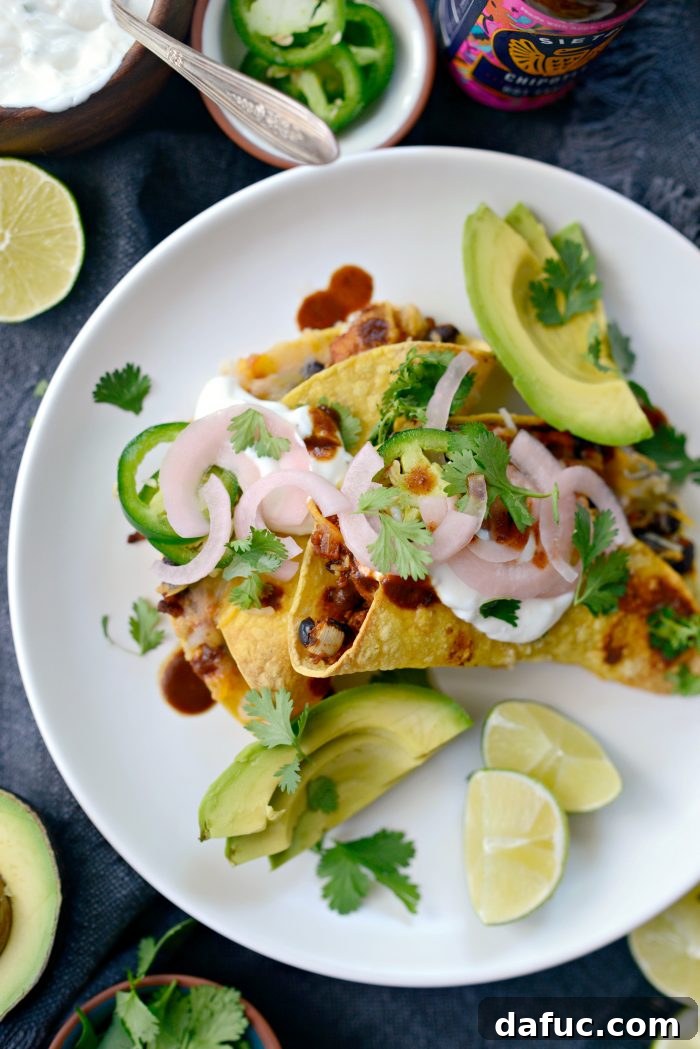 A vibrant spread of taco toppings including jalapeño crema, sliced avocado, pickled red onions, fresh cilantro, and hot sauce.