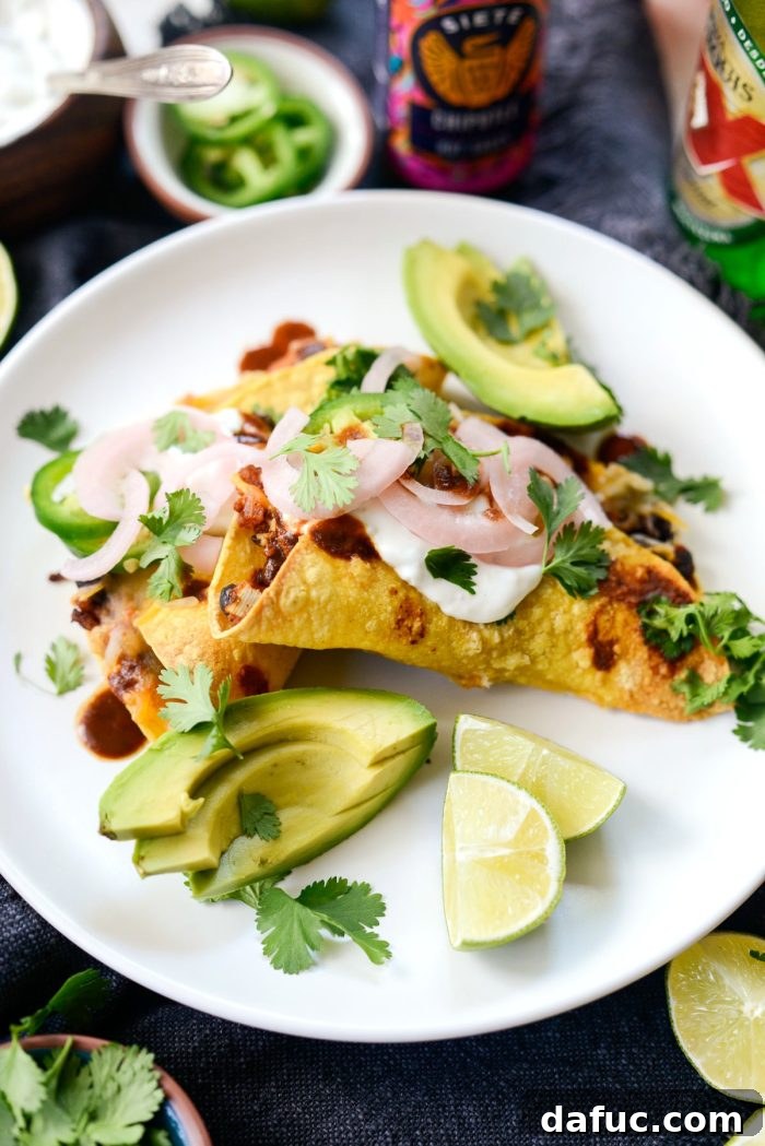Crisp air fried chipotle chicken black bean tacos on a white plate with various toppings arranged around them.