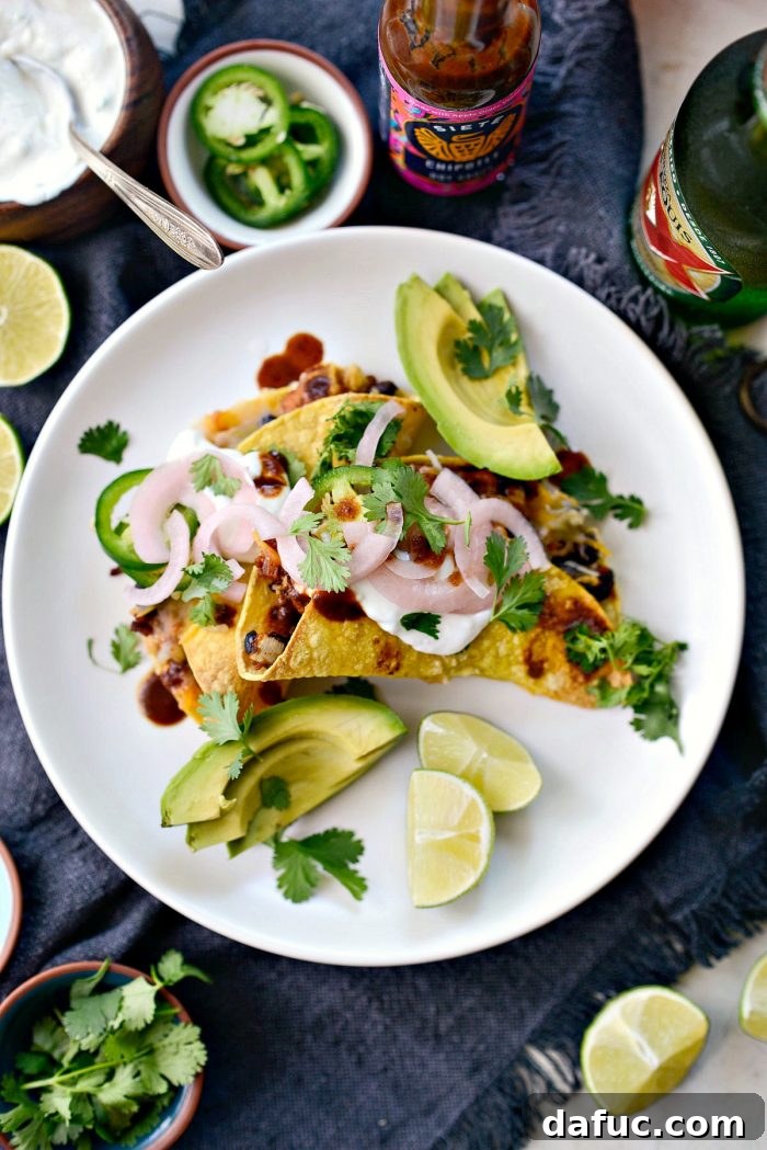 Air fried chipotle chicken black bean tacos on a white plate, garnished with fresh cilantro and a side of jalapeño crema.