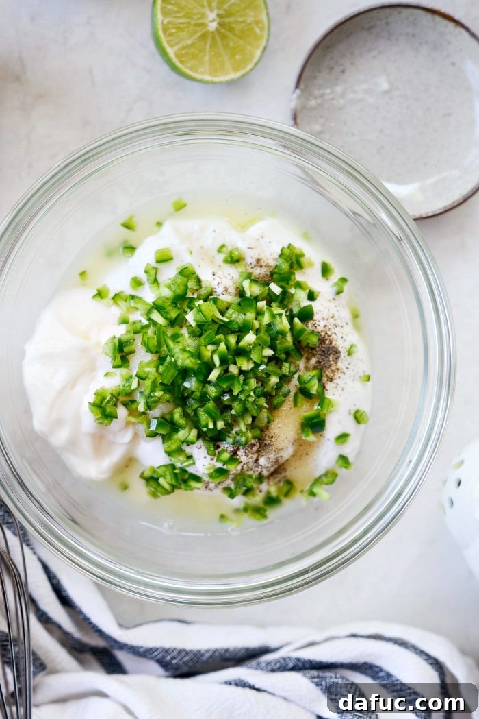 All ingredients for jalapeño crema mixed together in a white bowl with a whisk.