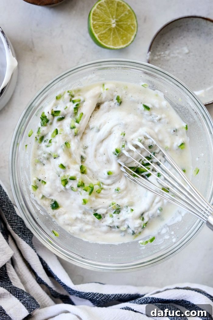 Jalapeño crema whisked to a smooth consistency in a mixing bowl, ready to be covered and refrigerated.