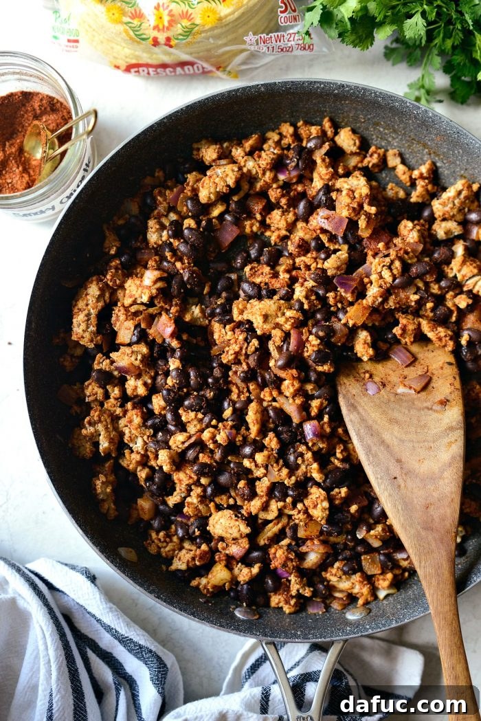Chipotle chicken and black bean taco filling ready in a skillet, stirred and removed from heat.