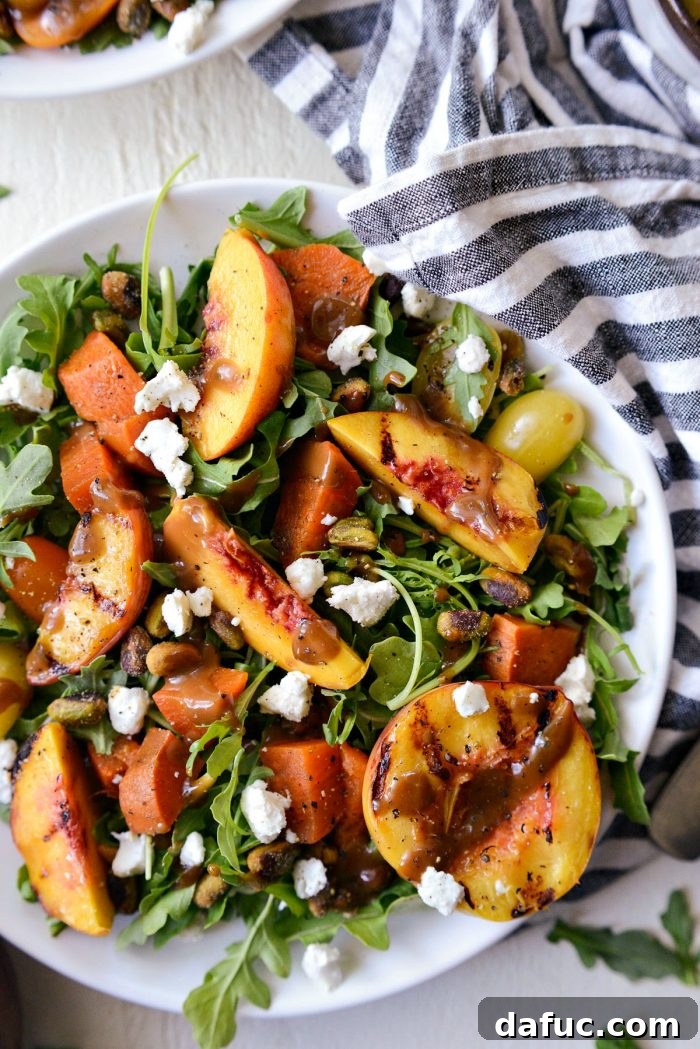 A generous serving of Grilled Peach and Sweet Potato Arugula Salad, drizzled with dressing