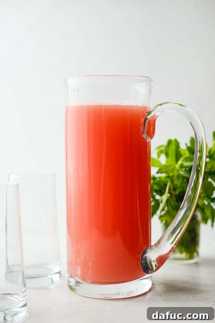 A large glass pitcher filled with freshly made watermelon lemonade, ready for serving.