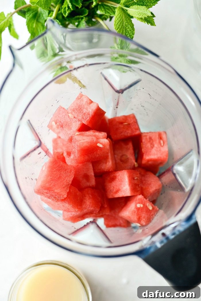 Close-up of cubed seedless watermelon being added to a large blender.