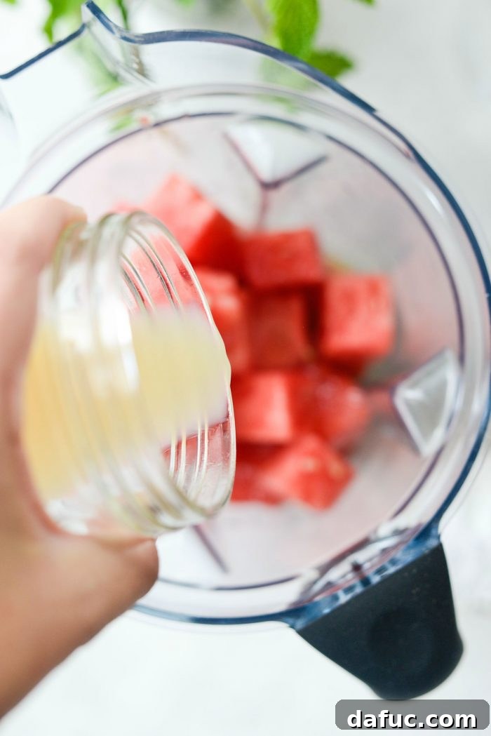 Pouring fresh lemon juice into the blender with watermelon cubes.