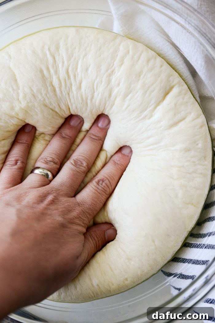 Roman Cheese and Pepper Pizza 5 Pizza dough being gently pressed down to release air after rising