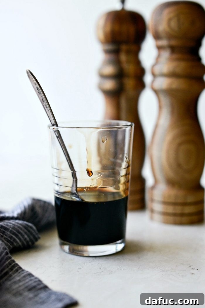 Homemade balsamic glaze in a clear glass with a spoon inside