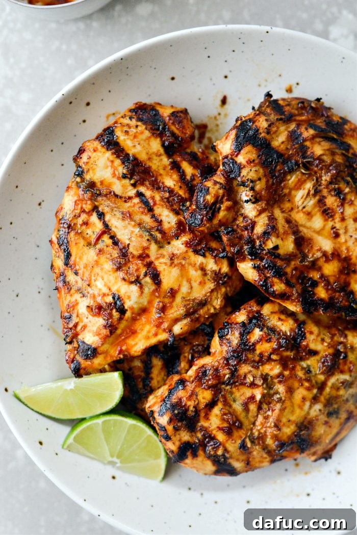 Signature Chipotle Chicken Marinade 2 A perfectly grilled, juicy piece of chipotle chicken, invitingly placed on a cutting board, ready to be sliced and served, showcasing its vibrant color and tender texture.