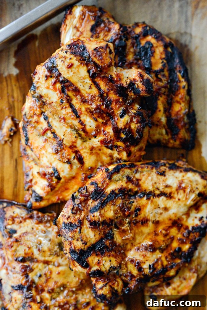 Signature Chipotle Chicken Marinade 11 Freshly grilled chipotle chicken resting on a rustic wooden cutting board, with vibrant green cilantro scattered nearby, ready to be sliced for various delicious meals.
