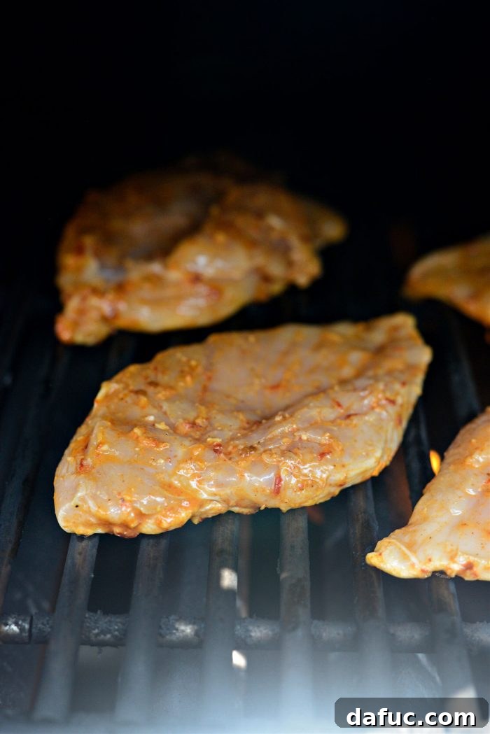 Signature Chipotle Chicken Marinade 10 Chipotle marinated chicken breasts sizzling beautifully on a hot outdoor grill, showing perfect, dark grill marks and a appetizing char developing on the surface.