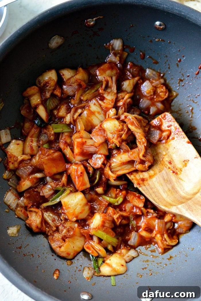 Ultimate Kimchi Fried Rice 11 The kimchi and sauce mixture heating through and simmering in the wok, releasing its incredible aroma.