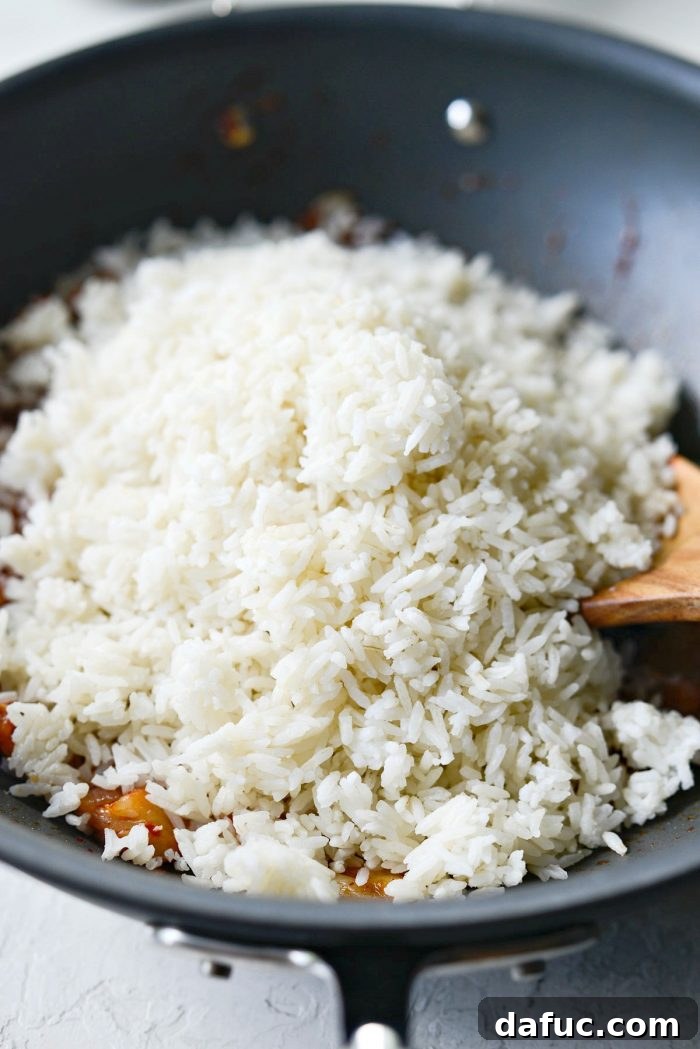 Ultimate Kimchi Fried Rice 12 Day-old cooked jasmine rice being added to the flavorful kimchi stir-fry in the wok.
