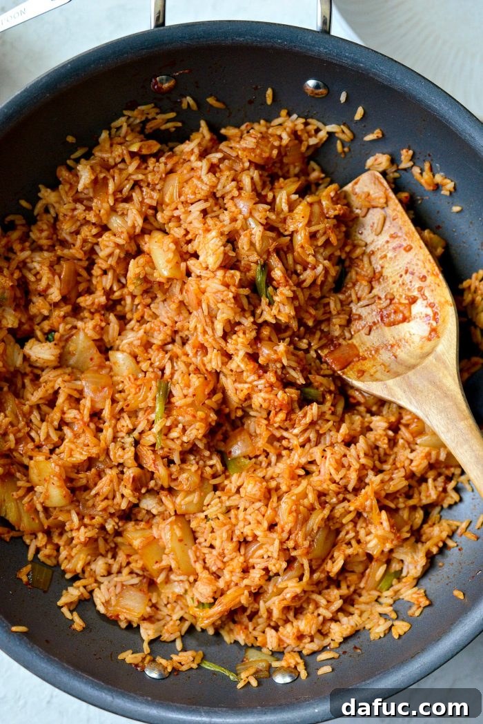 Ultimate Kimchi Fried Rice 14 The finished kimchi fried rice cooking in a wok, filling the air with its delicious scent.