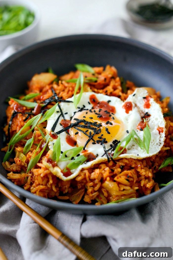 Ultimate Kimchi Fried Rice 3 Kimchi fried rice served in a sleek black bowl with chopsticks, ready to be enjoyed.