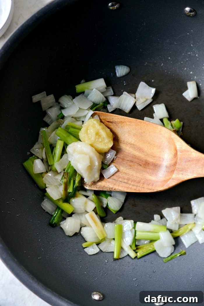 Ultimate Kimchi Fried Rice 8 Freshly grated garlic and ginger being added to sautéed vegetables in a wok.