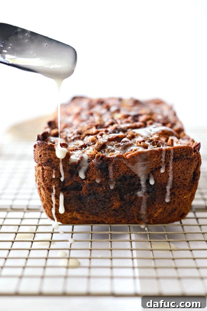 Cinnamon Apple Fritter Bread 21 Yogurt glaze being drizzled over a cooled loaf of Dutch Apple Fritter Bread