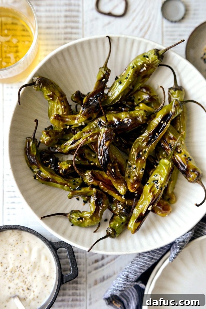 Sesame-Kissed Blistered Shishito Peppers with Zesty Lemon Garlic Aioli 15 Blistered shishito peppers arranged in a bowl, garnished with sesame seeds and flaky salt
