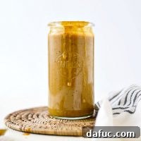 A bowl of Carolina Mustard BBQ Sauce with a spoon, ready to be served.