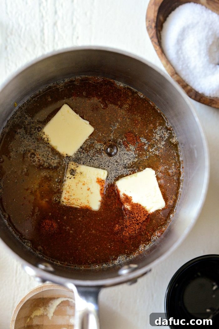 Distilled white vinegar, water, and unsalted butter being added to the saucepan with the mustard, sugar, and spice mixture.