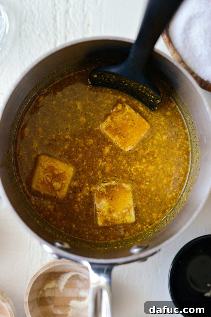 All Carolina Mustard BBQ Sauce ingredients are combined in a saucepan and stirred, showing a smooth, golden consistency before heating.
