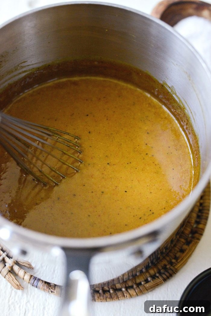 Carolina Mustard BBQ Sauce being whisked until smooth in a saucepan, with a rich, golden color.