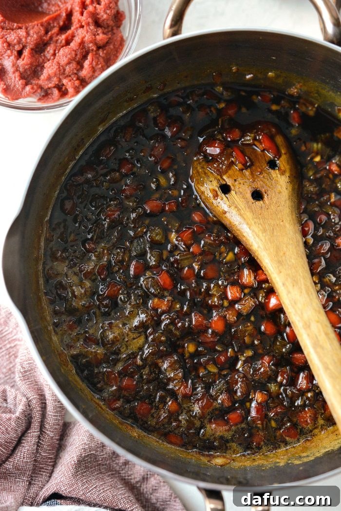 A spoonful of the thickened and fragrant Coca-Cola Habanero BBQ Sauce, showcasing its rich texture after simmering.
