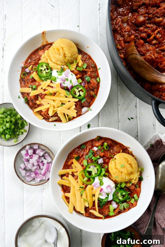 Fireside Smoky Pulled Pork Chili 13 Bowl of Smoky Pulled Pork Chili with various toppings including corn cake and cheese