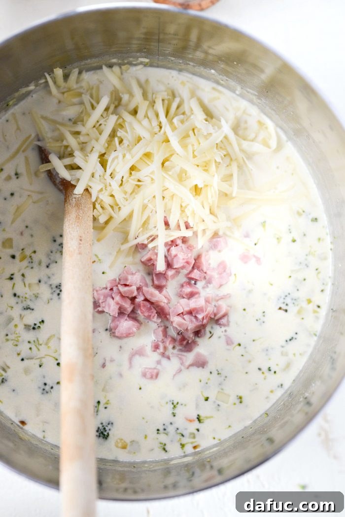 Hearty Ham, Swiss & Broccoli Delight 17 Grated Gruyere cheese and diced ham being stirred into the creamy soup.