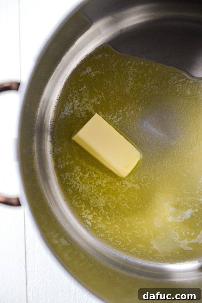 Hearty Ham, Swiss & Broccoli Delight 5 Unsalted butter melting in a gleaming stainless steel soup pot, ready for the next step in making a creamy soup.