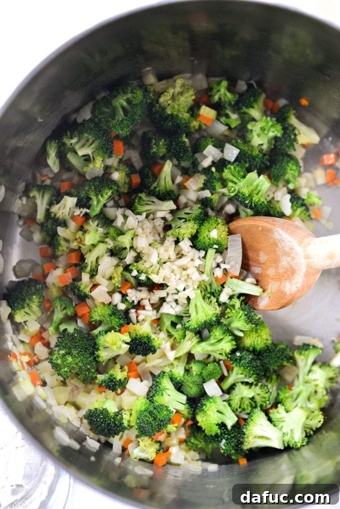 Hearty Ham, Swiss & Broccoli Delight 10 Minced garlic being added to the pot with partially cooked vegetables, filling the air with aroma.