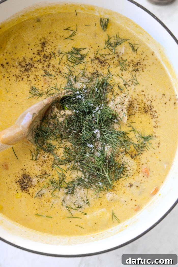Coastal Catch Salmon Chowder 19 Fresh chopped dill being sprinkled into the cooked salmon chowder, alongside a bowl of kosher salt and a pepper grinder for seasoning.