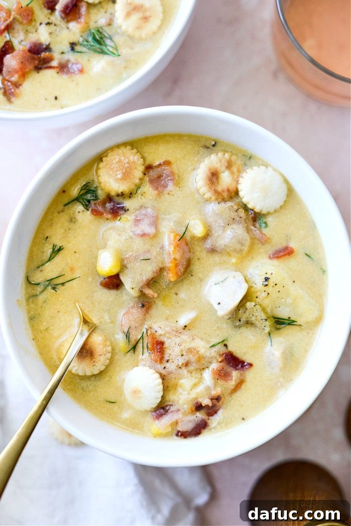 Coastal Catch Salmon Chowder 23 A gold spoon resting in a white bowl filled with creamy salmon chowder, highlighting the rich texture.