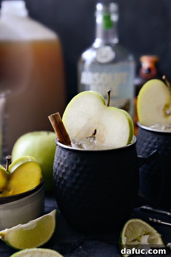Orchard Mule 2 A refreshing Apple Cider Moscow Mule cocktail in a copper mug, garnished with apple slices and a cinnamon stick, evoking the cozy flavors of autumn.