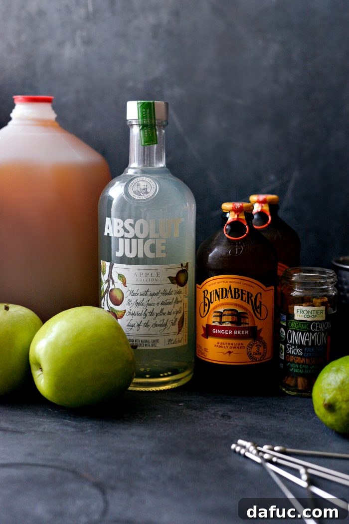 Orchard Mule 4 All the ingredients for Apple Cider Moscow Mules laid out: apple vodka, fresh apple cider, ginger beer, limes, cinnamon sticks, and apple slices.