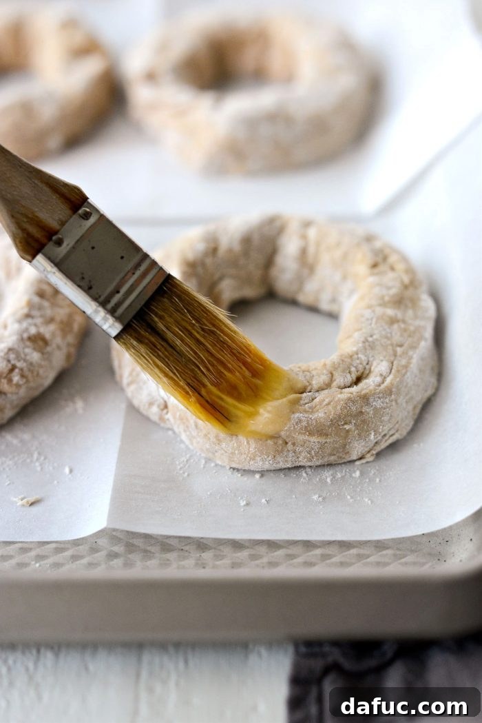 Delicious Air Fryer Pumpkin Spice Bagels 17 Brushing an unbaked bagel with egg wash.