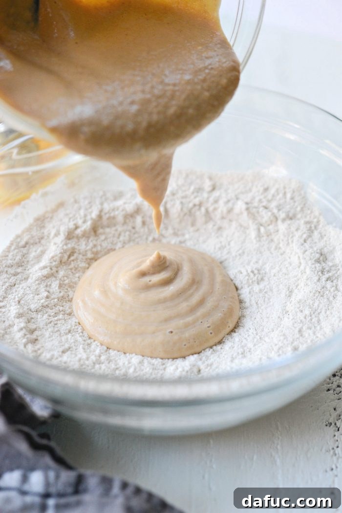 Delicious Air Fryer Pumpkin Spice Bagels 9 Pouring the combined wet ingredients into the bowl with the dry ingredients for the bagel dough.