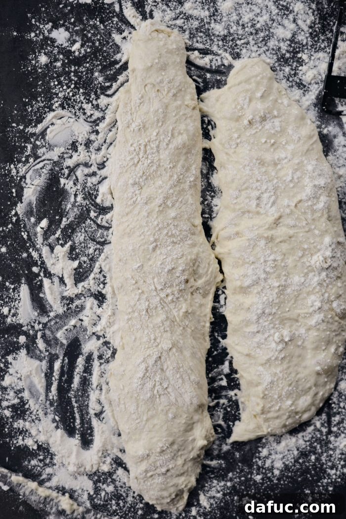 Shaping no-knead dough into a baguette form with gentle folds.