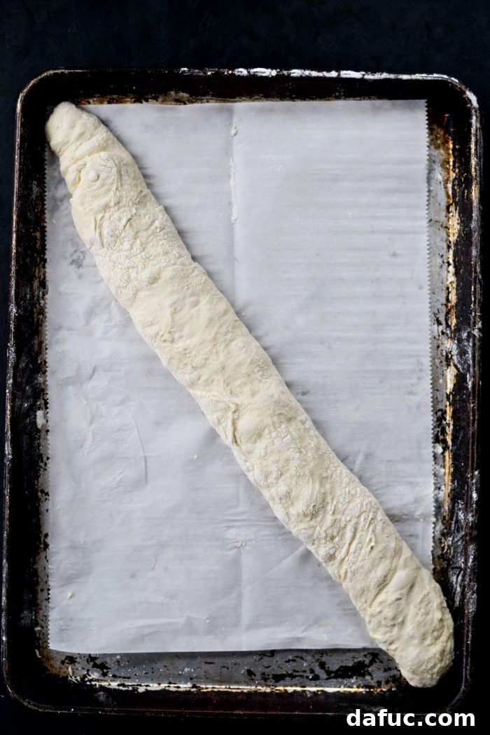 Carefully turning the shaped dough onto parchment paper using a bench scraper.