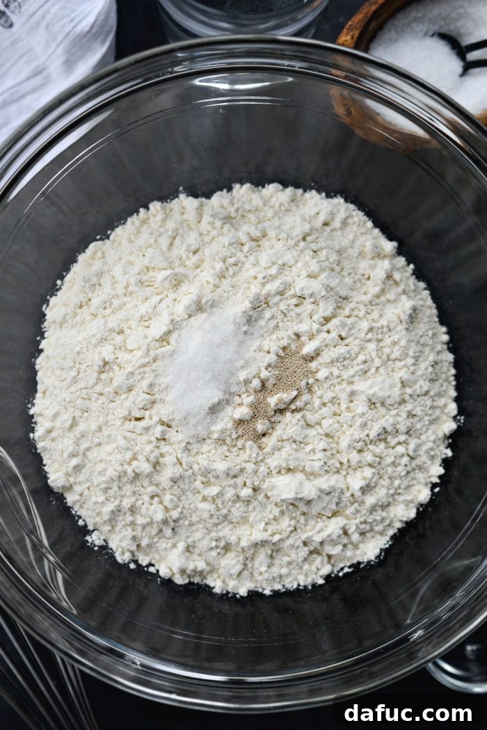 A close-up of artisan bread flour, kosher salt, and active dry yeast, the dry ingredients for No-Knead French Bread.