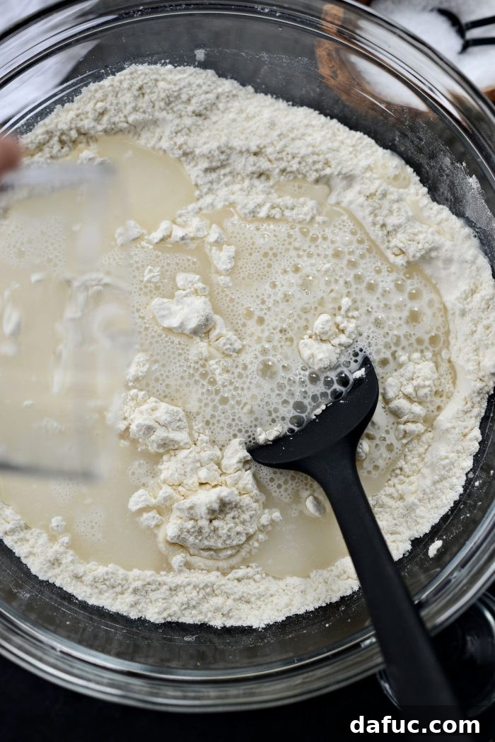 Gradually stirring water into the dry ingredients for the dough.