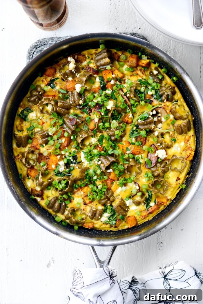 Roasted Pumpkin Kale and Feta Frittata in skillet with green onion and minced parsley.