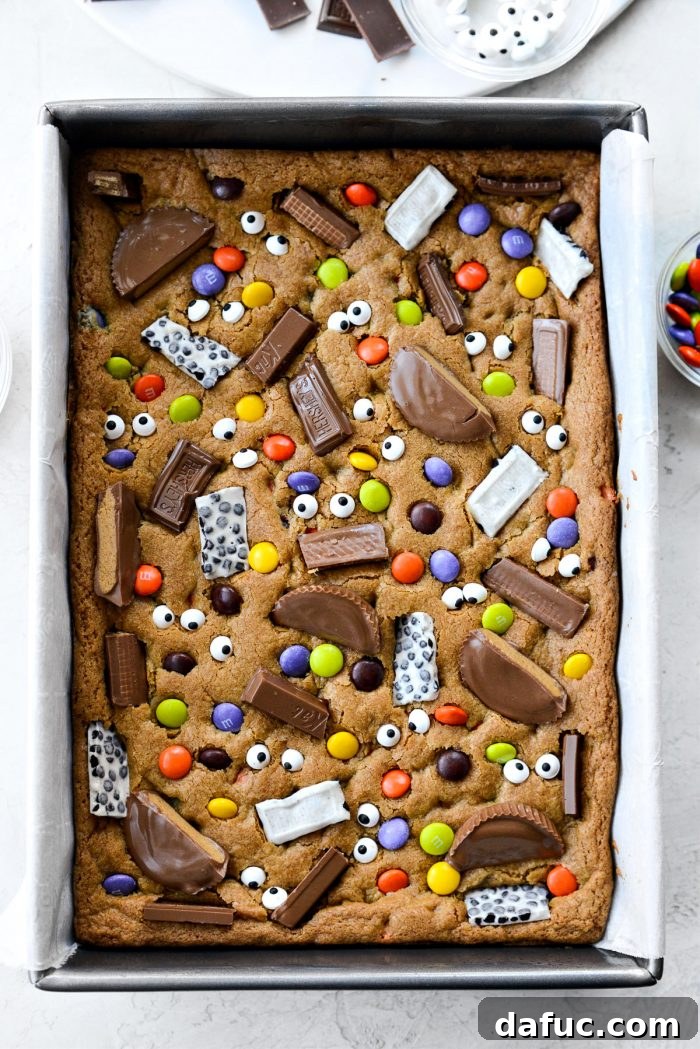 Halloween Haul Cookie Bars 18 A pan of freshly baked Halloween Candy Cookie Bars, ready for the candy toppings to be pressed in.