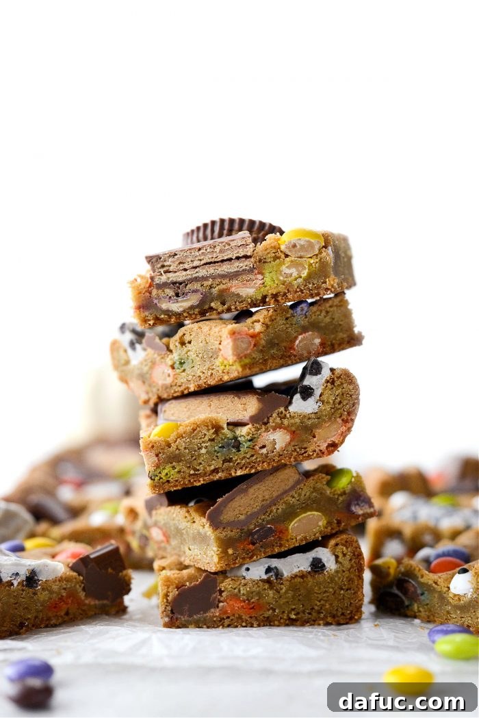 Halloween Haul Cookie Bars 3 Deliciously stacked Halloween Candy Cookie Bars, showcasing a generous topping of assorted chocolates and colorful candies.