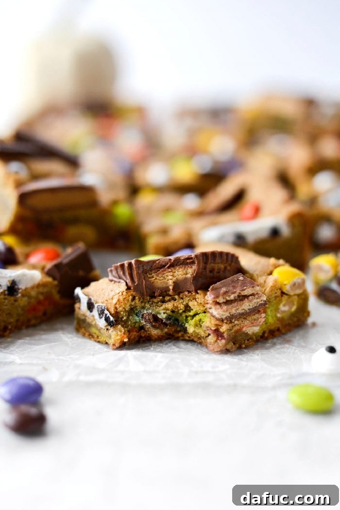 Halloween Haul Cookie Bars 21 A person taking a delicious bite into a Halloween Candy Cookie Bar, showing the soft interior and candy toppings.