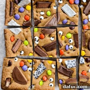 Halloween Haul Cookie Bars 23 A single Halloween Candy Cookie Bar on a white background, highlighting its rich texture and colorful candy toppings.
