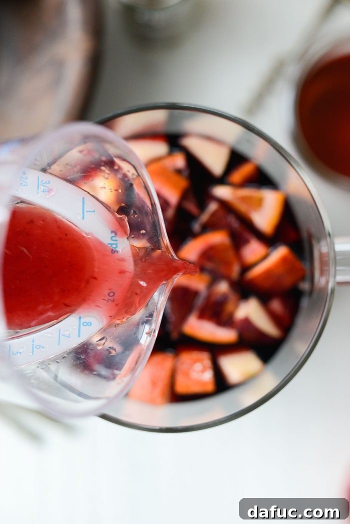 Ruby Fizz Sangria 12 Pouring freshly squeezed blood orange juice into the pitcher
