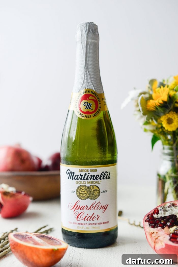 Bottle of sparkling apple cider next to a pitcher of sangria