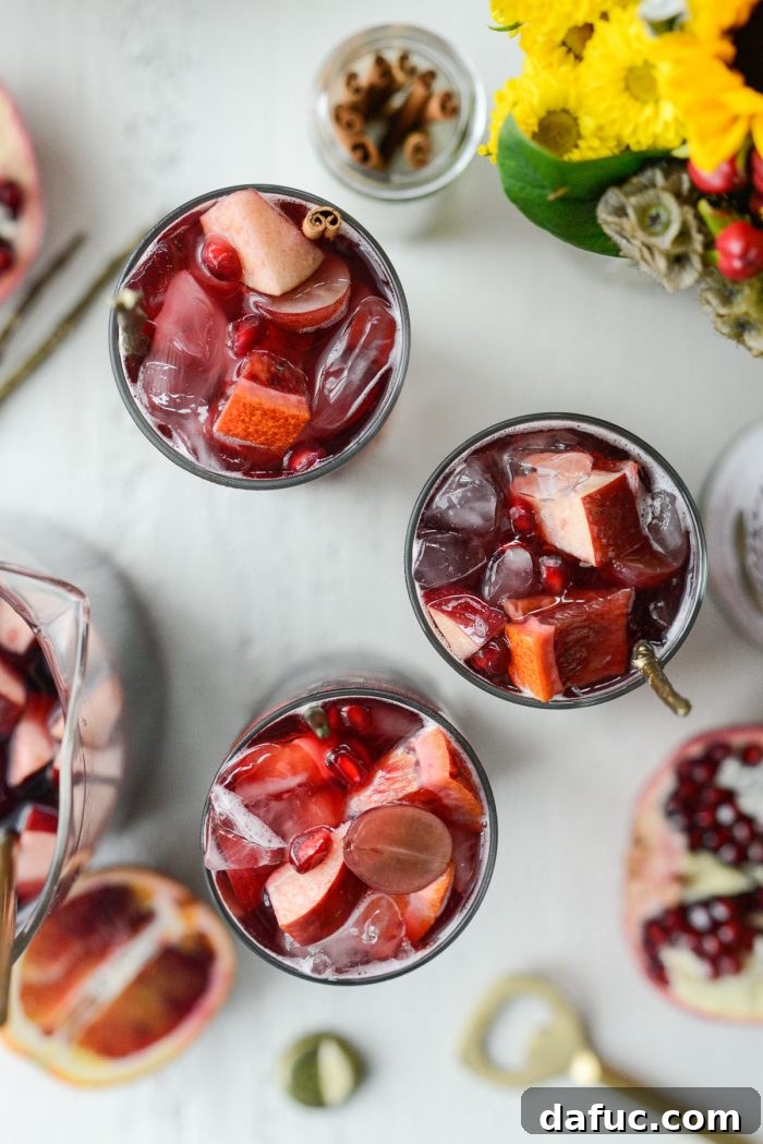 Group shot of glasses and pitcher of Pomegranate Sparkling Apple Cider Sangria on a wooden table